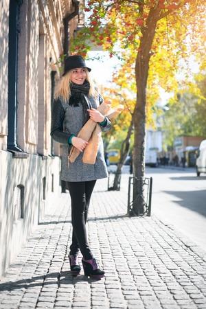 Young beautiful woman with a loaf of bread in her hands in autumn. Outdoors portrait.の写真素材