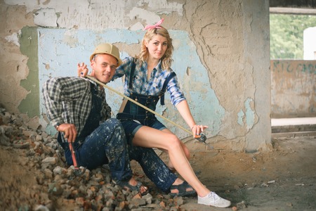 Portrait of a young man and woman in overalls with tools in a newly built house. Concept of construction and home repair.の写真素材