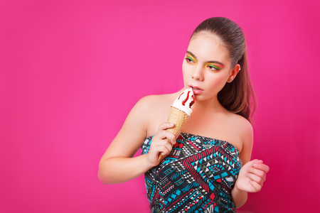 Portrait of beautifull woman with ice cream over pink background in the studio. Copy space.の写真素材