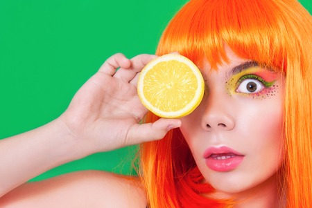 Portrait of red-haired woman in studio close-up with lemon in hand.の写真素材