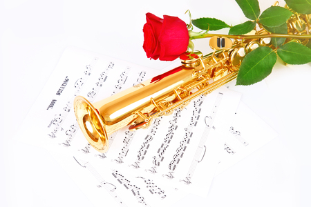 Red rose, saxophone and music sheet on a white backgroundの写真素材