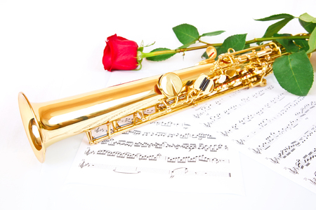 Red rose, saxophone and music sheet on a white backgroundの写真素材