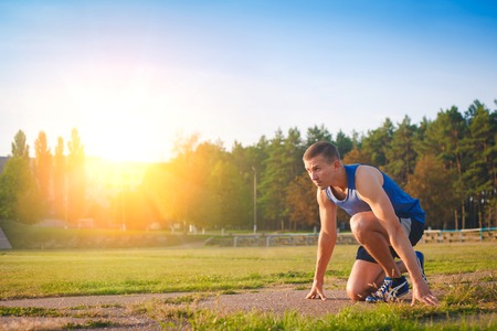 Man in low start position on old stadium. Athlete in starting position. Running, jogging, cardio, sport, active lifestyle concept.の写真素材
