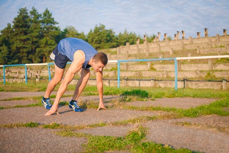 Man on a high start position on old stadium. Athlete in starting position. Running, jogging, cardio, sport, active lifestyle concept.の写真素材
