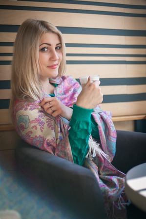 Close-up portrait of a beautiful woman with a cup of coffee at a cafeの写真素材