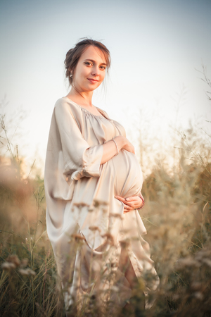 Portrait of a pregnant woman in the sunset light on the nature of the fieldの写真素材