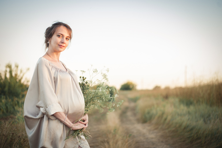 Portrait of a pregnant woman in the sunset light on the nature of the fieldの写真素材