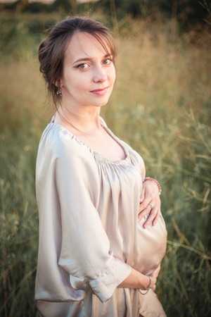Portrait of a pregnant woman in the sunset light on the nature of the fieldの写真素材
