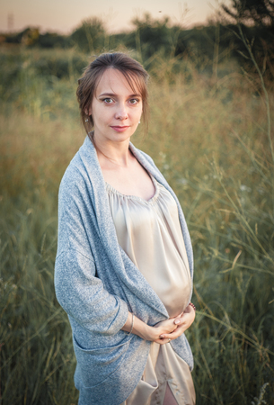 Portrait of a young beautiful pregnant woman on nature in the sunset light.の写真素材