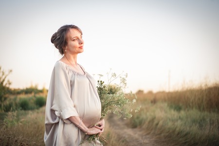 Portrait of a young beautiful pregnant woman on nature in the sunset light.の写真素材