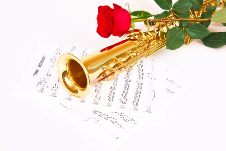 Red rose, saxophone and music sheet on a white backgroundの写真素材