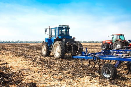 Two tractors with a plow in a field on a sunny day. The concept of work in a fields and agriculture industry.の写真素材