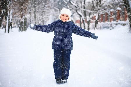 Small girl playing with snow in a park. Wonderful snowy day. The concept of childhood and the winter season.の写真素材