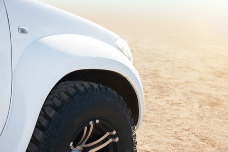 Close up of white car on the sand on a bright sunny day.の写真素材