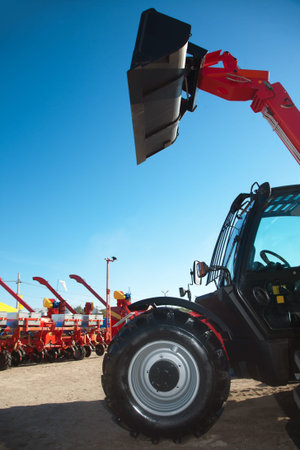 Excavator with bucket and sowing machinery on the background.