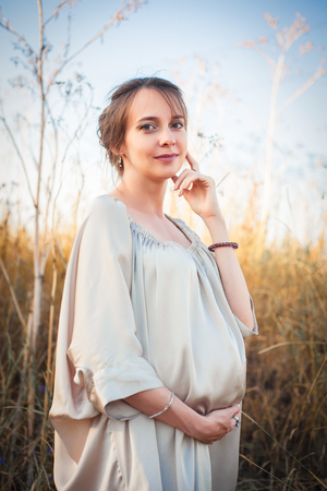 Portrait of a pregnant woman in the sunset light on the nature of the fieldの写真素材