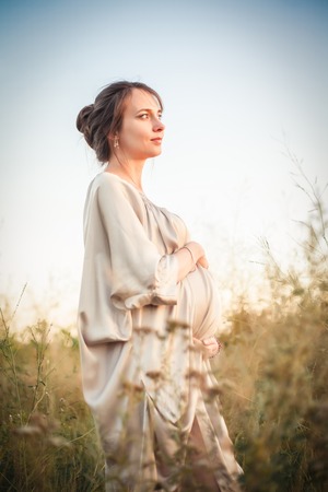 Portrait of a pregnant woman in the sunset light on the nature of the fieldの写真素材