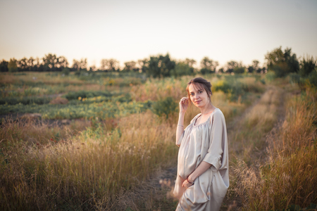 Portrait of a pregnant woman in the sunset light on the nature of the fieldの写真素材