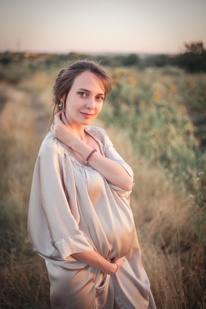 Portrait of a young beautiful pregnant woman on nature in the sunset light.の写真素材