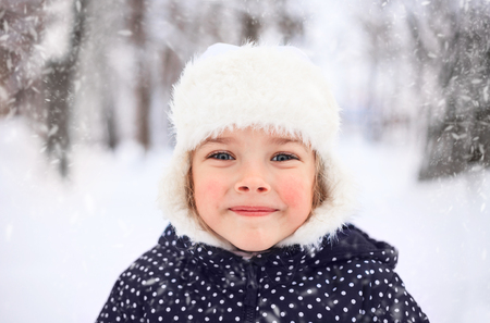 Portrait of a cute little girl in a snowy winter weather.の写真素材