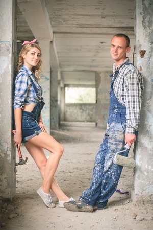Portrait of a young man and woman in overalls with tools for the repair of the interior in hands. Concept of construction and home repair.の写真素材