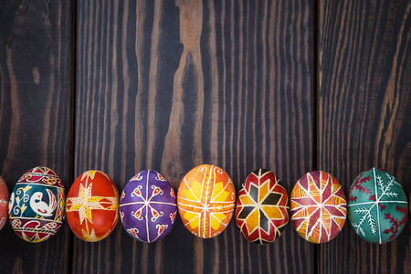 Easter eggs in a row on a dark wooden background.の写真素材