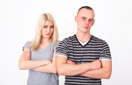 Offended couple standing with crossed arms in studio and looking at camera.の写真素材