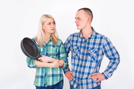 Man and woman quarrel. A woman with a frying pan in his hands. Humorous concept of a family quarrel.の写真素材
