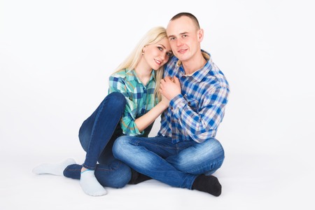 Romantic young couple sitting on floor, holding hands in studio.の写真素材