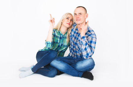 Romantic young couple sitting on floor cuddling, in studio.の写真素材