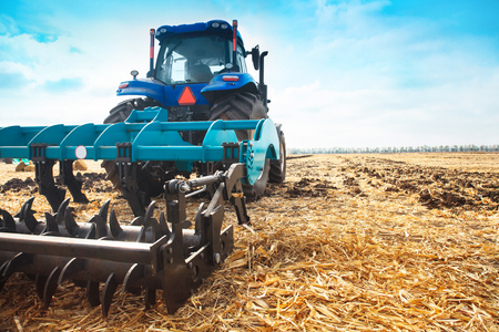 Modern tractor in a field on a sunny day.. The concept of work in a fields and agriculture industry.の写真素材