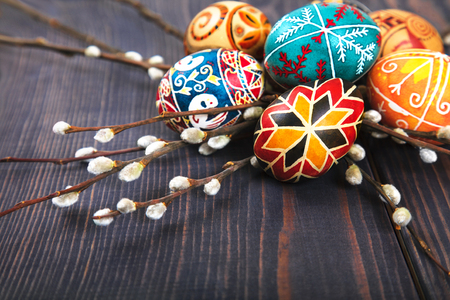 Easter eggs with willow twigs on a wooden plank table. The concept of the Easter holidays, and folk art.の写真素材