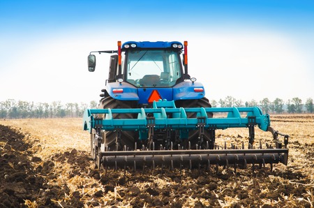 Modern tractor in a field on a sunny day. The concept of work in a fields and agriculture industry.の写真素材