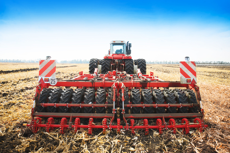 Modern tractor in the field with complex for the treatment and plowing of soil. The concept of work in a fields and agriculture industry.の写真素材
