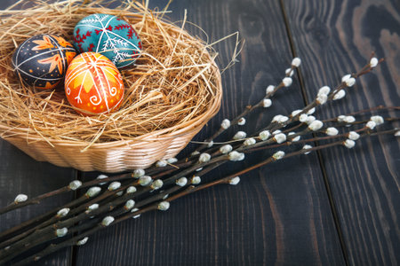 Easter eggs in a basket with willow twigs on a wooden table. The concept of the Easter holidays, and...