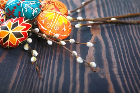 Easter eggs with willow twigs on a wooden plank table. The concept of the Easter holidays, and folk art.の写真素材