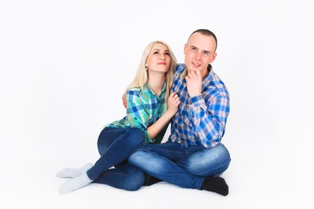 Romantic young couple sitting on floor cuddling, in studio.の写真素材