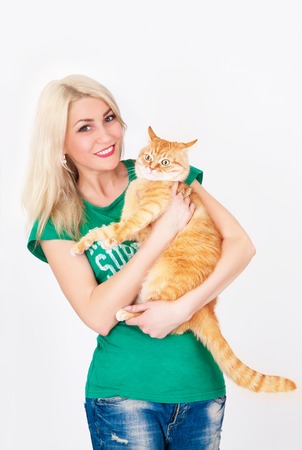 Young woman holds red cat in hands, in studio on white background.の写真素材