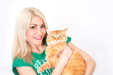 Young woman holds red cat in hands, in studio on white background.の写真素材