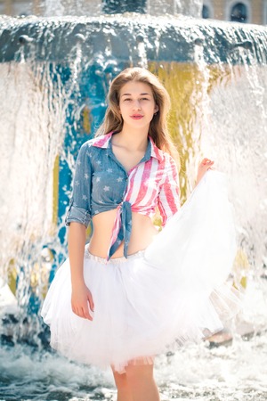 Cute young woman in fluffy skirt near the fountainの写真素材