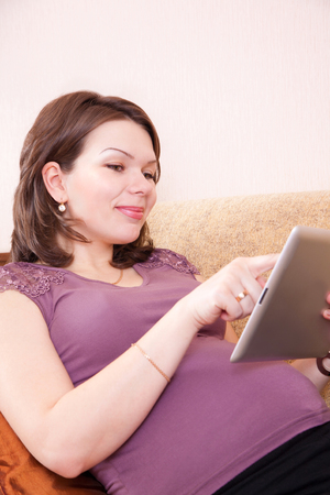 Happy pregnant woman, using a digital tabletの写真素材