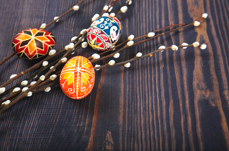 Easter eggs with willow twigs on a wooden plank table. The concept of the Easter holidays, and folk art.の写真素材
