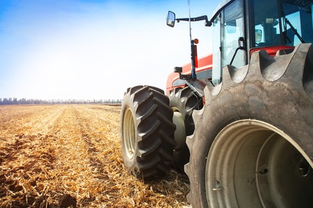 Modern red tractor in the field close-up on a bright sunny dayの写真素材