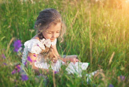Cute little girl reading book on natureの写真素材