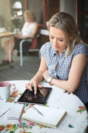 Young attractive woman in cafe uses a tablet for work.の写真素材