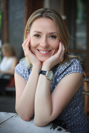 Fashion portrait of young woman sitting street cafe. Street fashion, smiling, happy, blonde, harmony. Authentic. Closeup portraitの写真素材