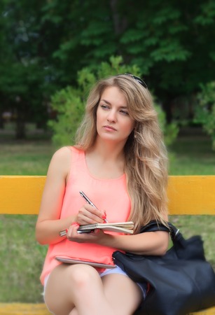 Beautiful young woman writes in a notebook.の写真素材