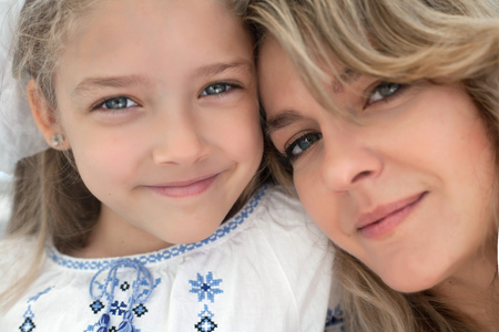 Close-up portrait of happy cheerful beautiful young mother with her little smiling daughter - outdoors.の写真素材