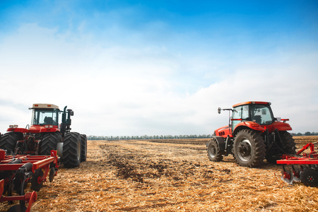 Two tractors with a plow in a field on a sunny day. The concept of work in a fields and agriculture industry.の写真素材