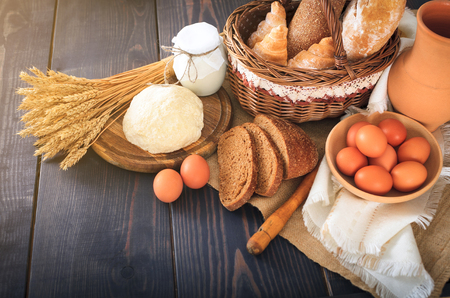 Breakfast from farm products: eggs, milk, fresh bread on a wooden table.の写真素材